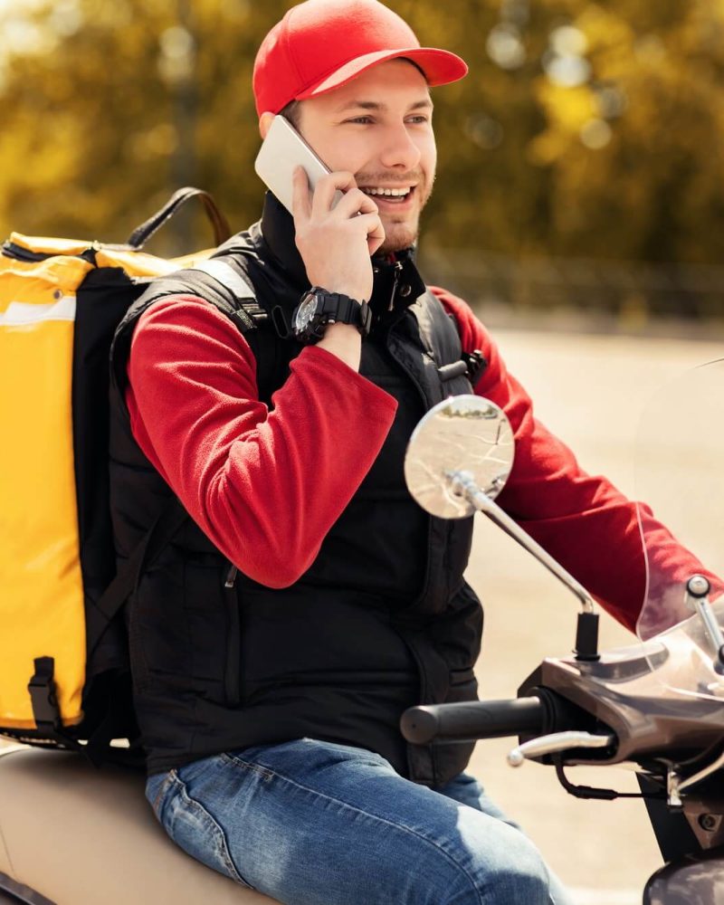 courier-talking-on-mobile-phone-sitting-on-scooter-in-city-1.jpg