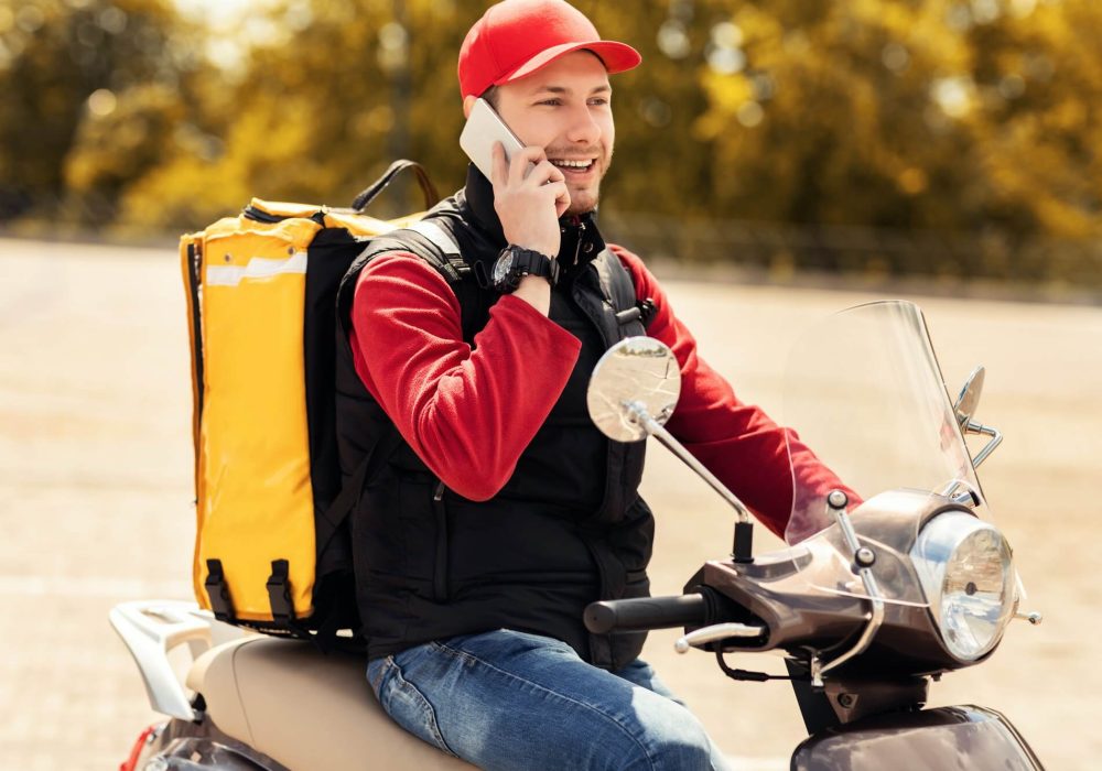 courier-talking-on-mobile-phone-sitting-on-scooter-in-city-1.jpg